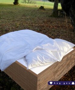 Weisse Kissenbezug aus Bio-Baumwolle draussen auf einem Naturbett
